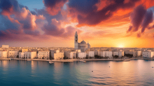 Panoramic photograph of Bari's historic center with the Basilica San Nicola and Bari Cathedral in the foreground and the Adriatic Sea in the background, under a vibrant sunset sky